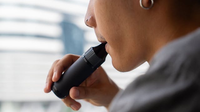 Close-up of a student exhaling from a vape device.